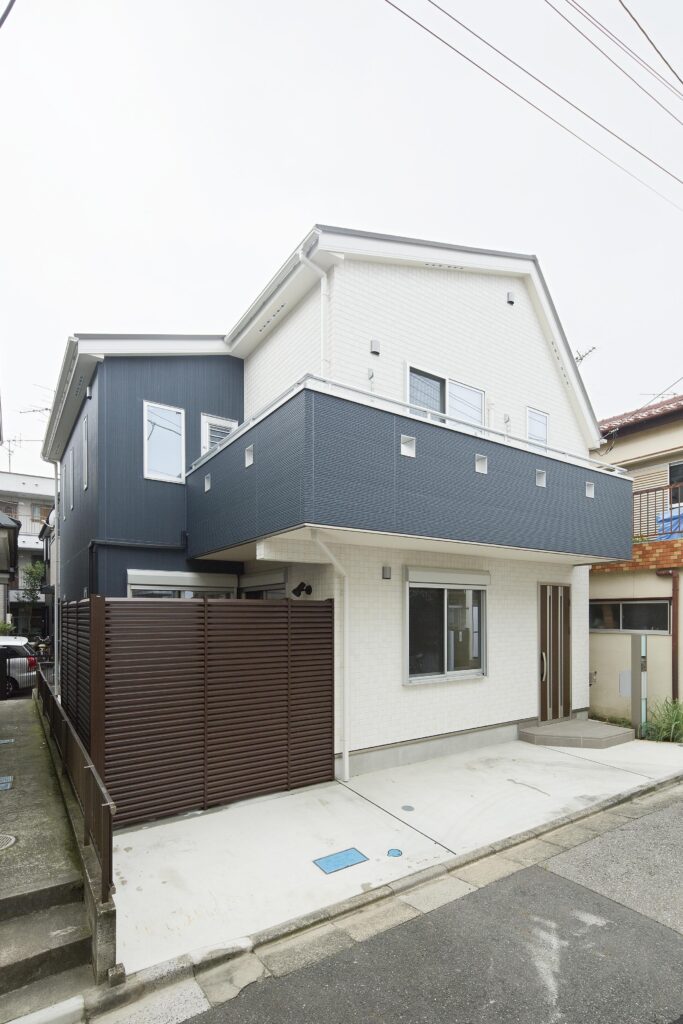 白と紺で落ち着いた雰囲気に。停めやすい駐車場もこだわりの一つ。横格子がウッドデッキを隠している。