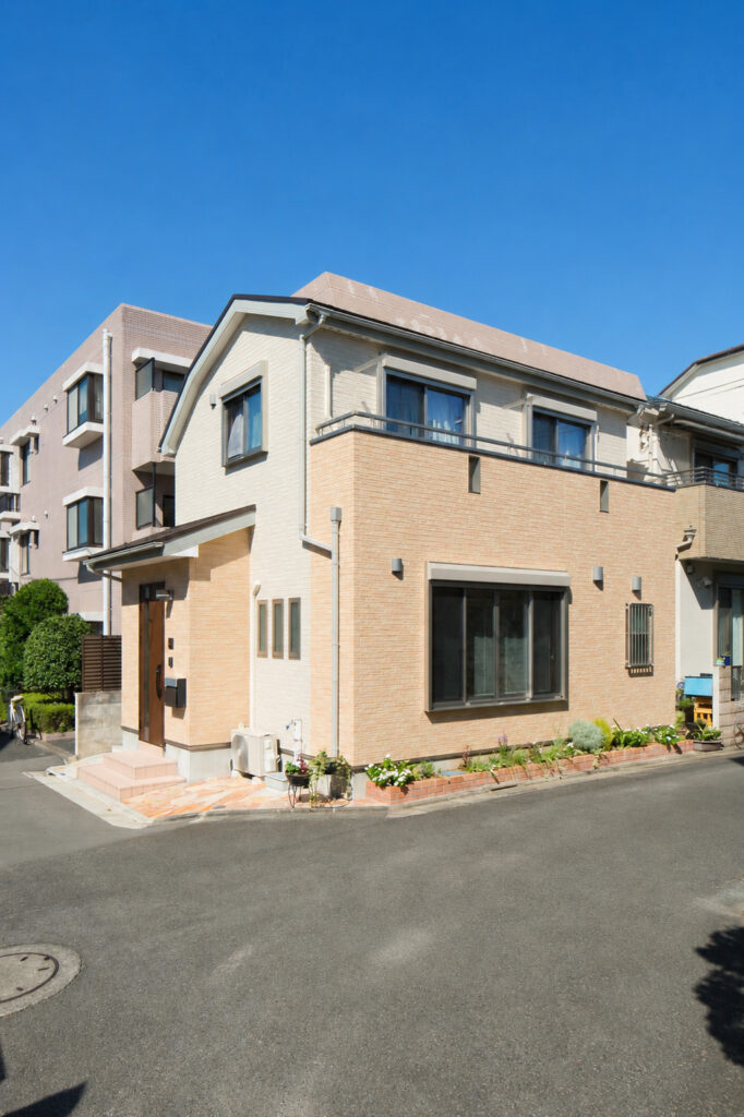 2色のベージュで彩った外観。塀ではなく、花壇で道路と仕切るのが奥様のこだわり。